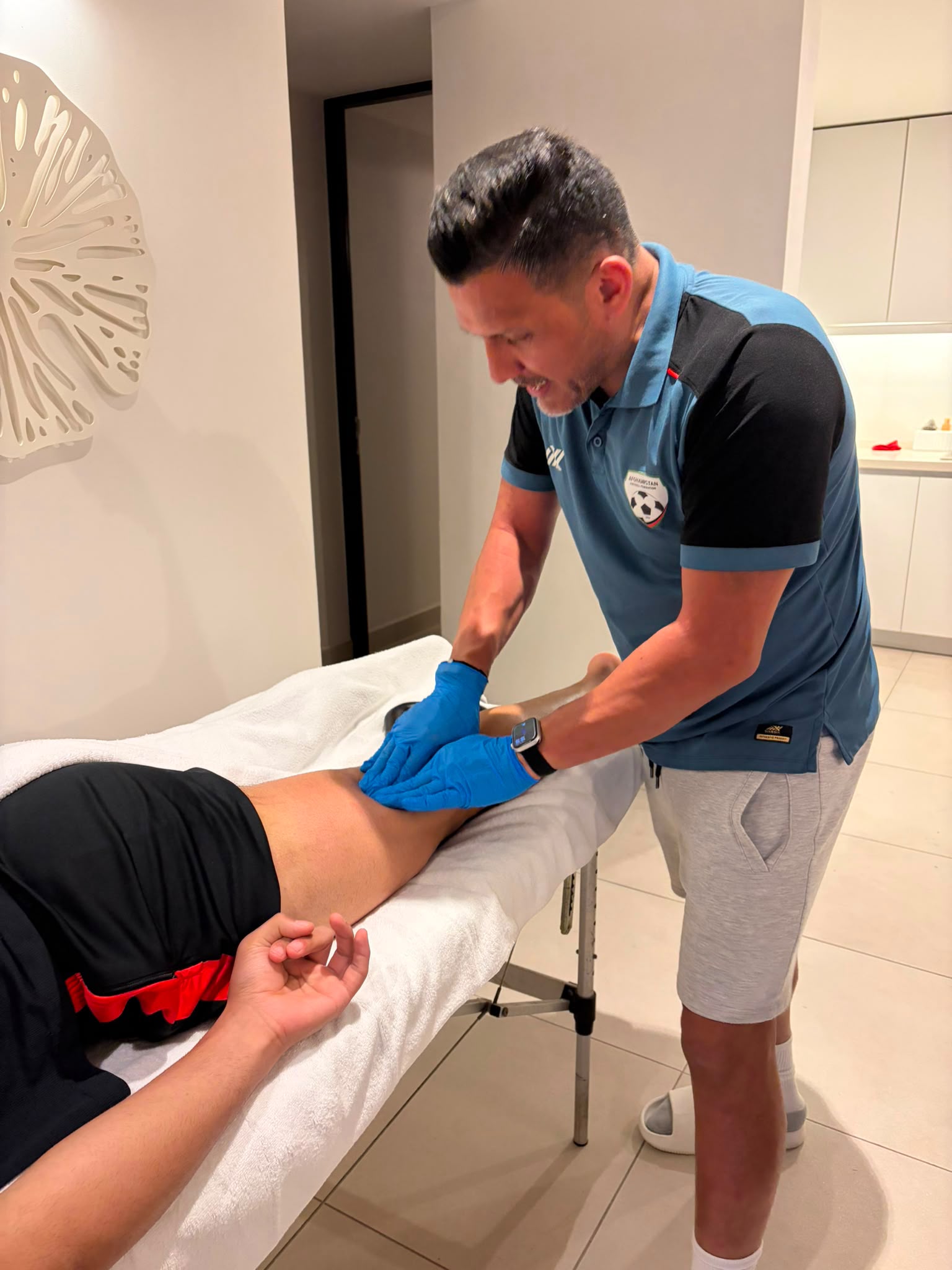 Amir Tamim Sultani palpating an elite athlete's hamstring during a mobile treatment session